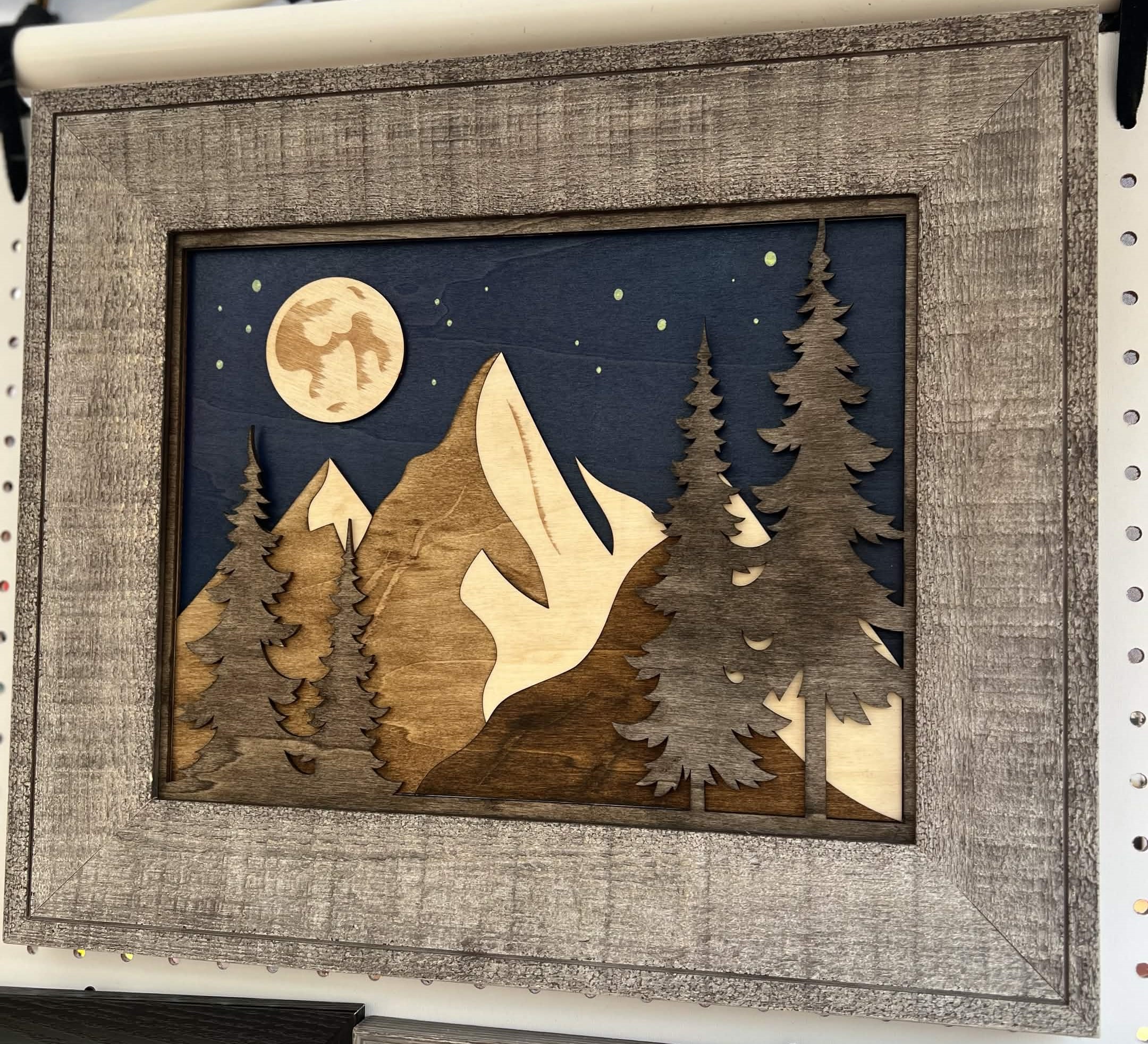 Layered wood art of a scenic mountain forest