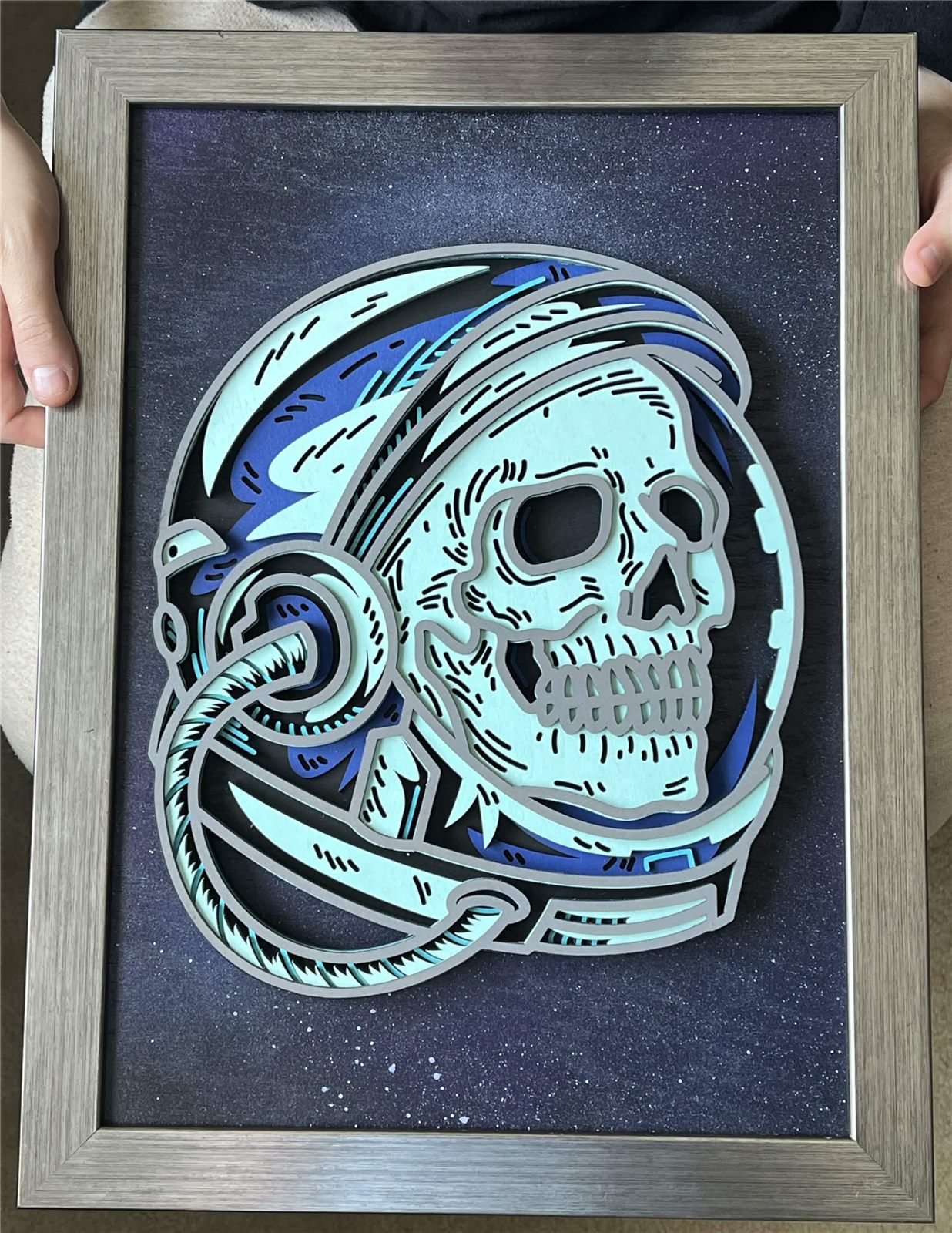 Layered wood art of an astronaut helmet with a skull inside